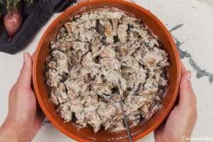 ingredients being stirred together to make the filling for stuffed mushroom casserole