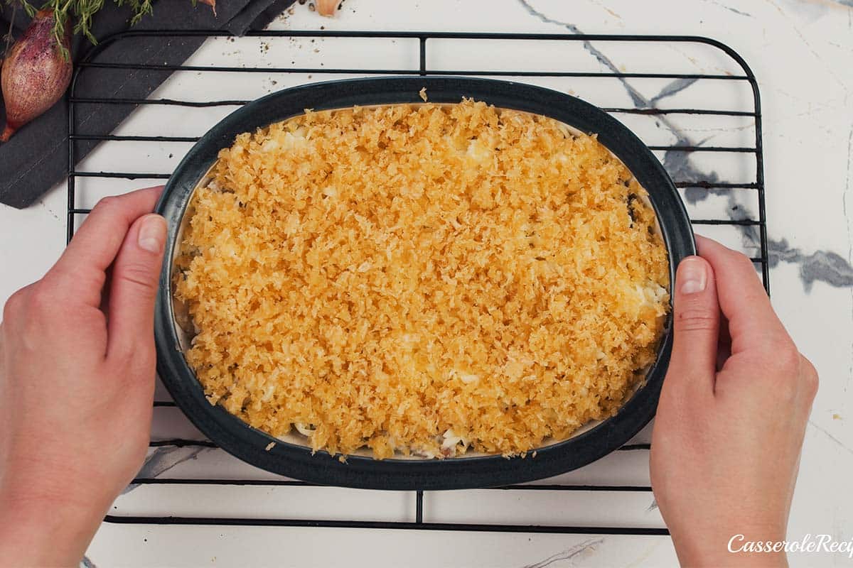 final step of topping the filling of stuffed mushroom casserole with breadcrumbs prior to baking