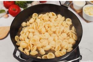 adding pasta to other ingredients to make Baked Orecchiette with Spinach